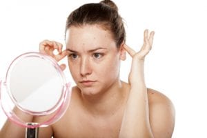 img-blog-thoughtful woman looking at herself in the mirror and squeeze her ears