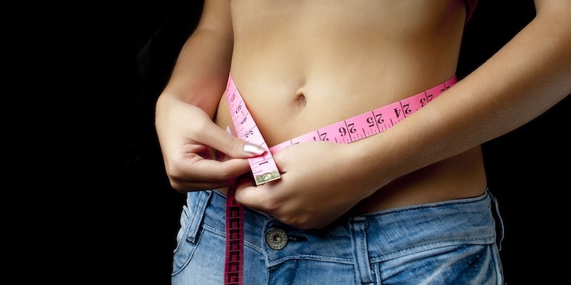 a woman measuring her waist