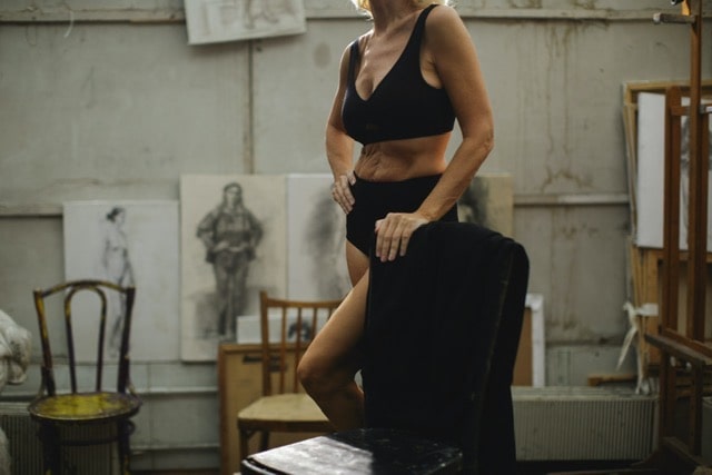 A woman posing for a painting wearing black undergarments