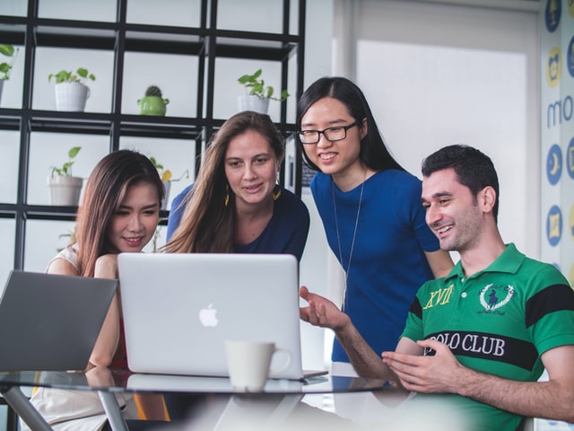 Several people gathered around a laptop.