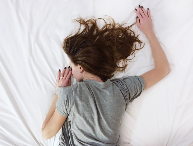 A girl resting on her bed, lying face-down.