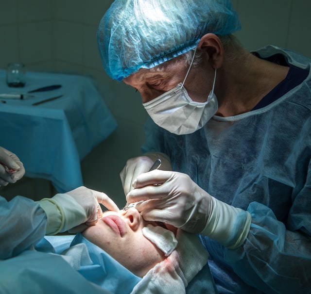 A plastic surgeon performing facial plastic surgery on a woman