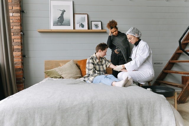 Doctor speaking to two people during a home visit.