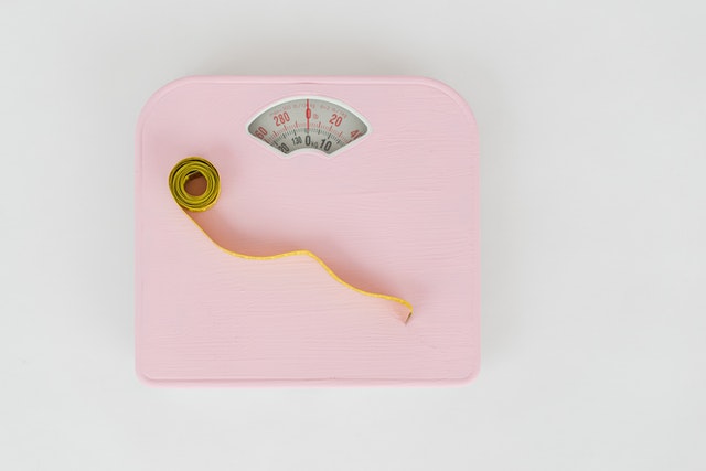 A pink weighing scale and a measuring tape.