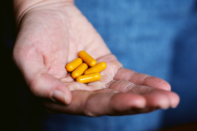 Close-up photo of a person holding yellow pills