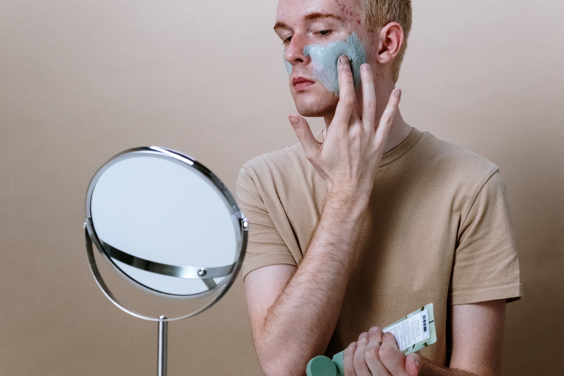 a man putting on face cream while looking in the mirror