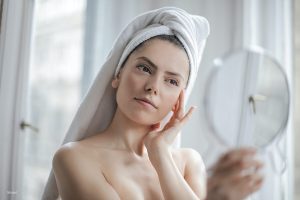 Woman with a towel on her head looking at a mirror