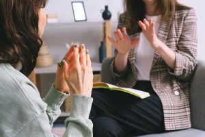 Woman talking to a therapist; one of the crucial steps to take if you're unhappy with your plastic surgery results