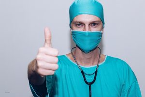 Doctor wearing scrubs and holding thumbs up