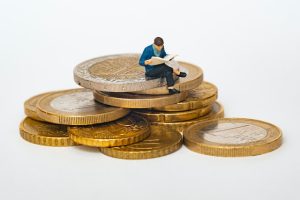 A man reading a newspaper and sitting on coins portraying that plastic surgery for men is for the wealthy