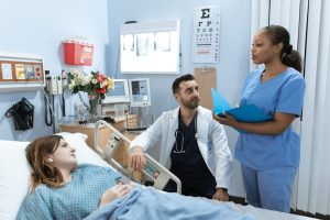 A woman lying in a hospital bed while talking to the nurse and the doctor. 