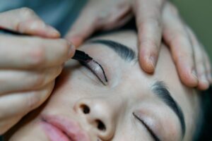 Surgeon preparing woman for an eyelid surgery.