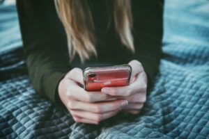 Person sitting and using a red iPhone.