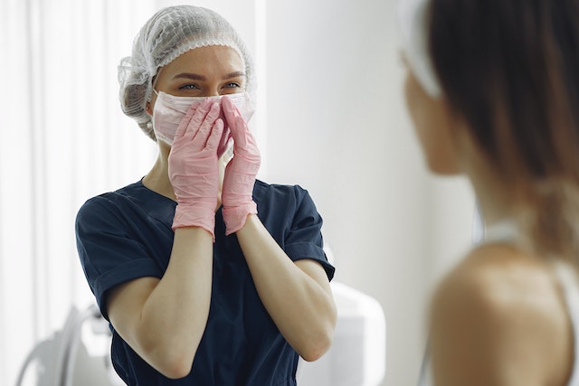 A happy woman standing with a mask and gloves after plastic surgery