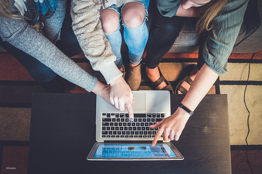  Three people sitting together, pointing at a laptop screen