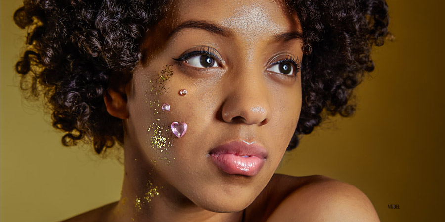 A beautiful woman of color with glitter and rhinestones on her face