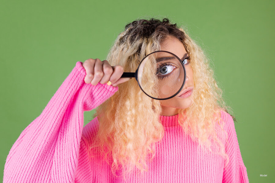 Woman looking through a magnifying glass.