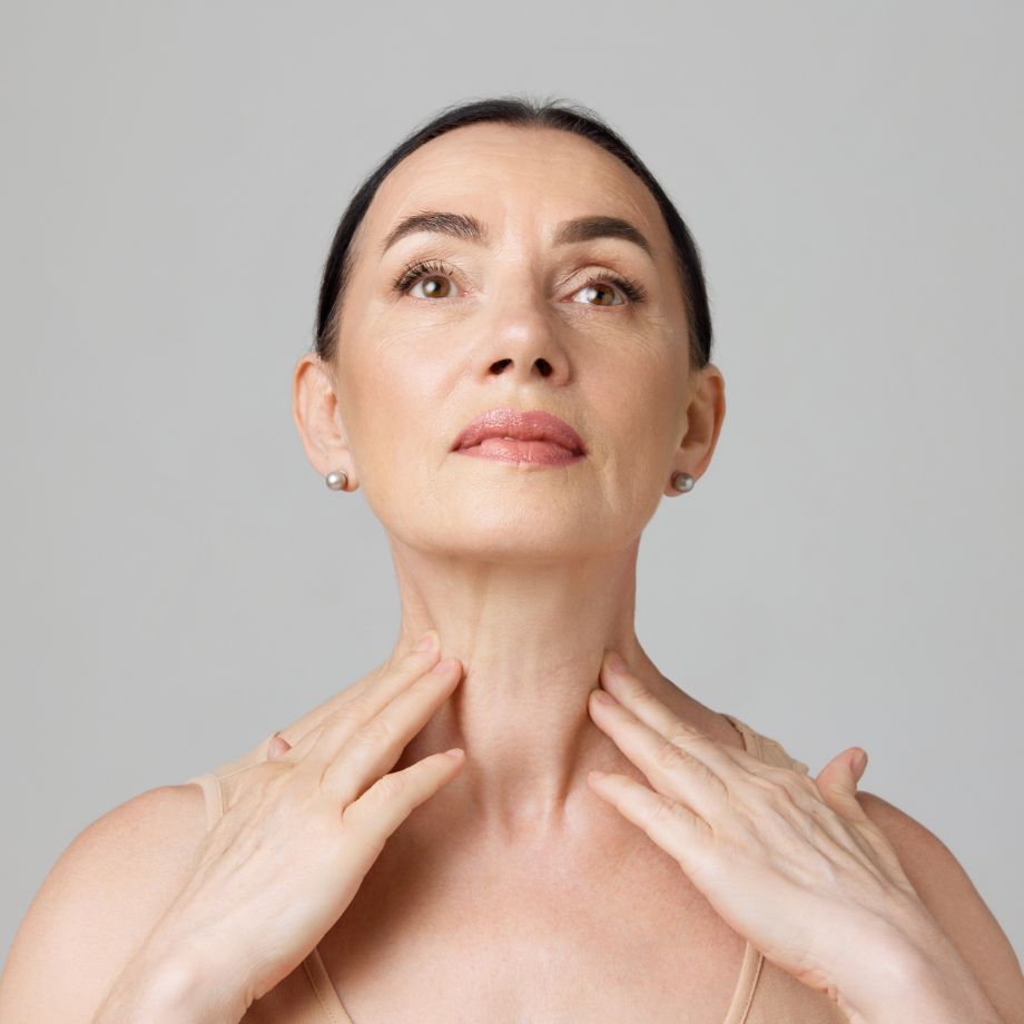 woman touching her bare shoulder and neck